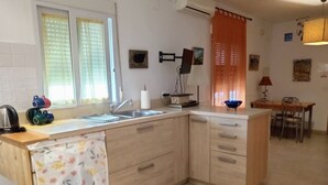 Uma cozinha compacta com pia, micro-ondas e um pequeno espaço de refeições com mesa e cadeiras.