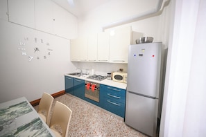 Cocina compacta con refrigerador, microondas, estufa y alacenas.
