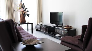 Ein modernes Wohnzimmer mit einer Couch, einem Couchtisch, einem Fernseher und einer dekorativen Vase.