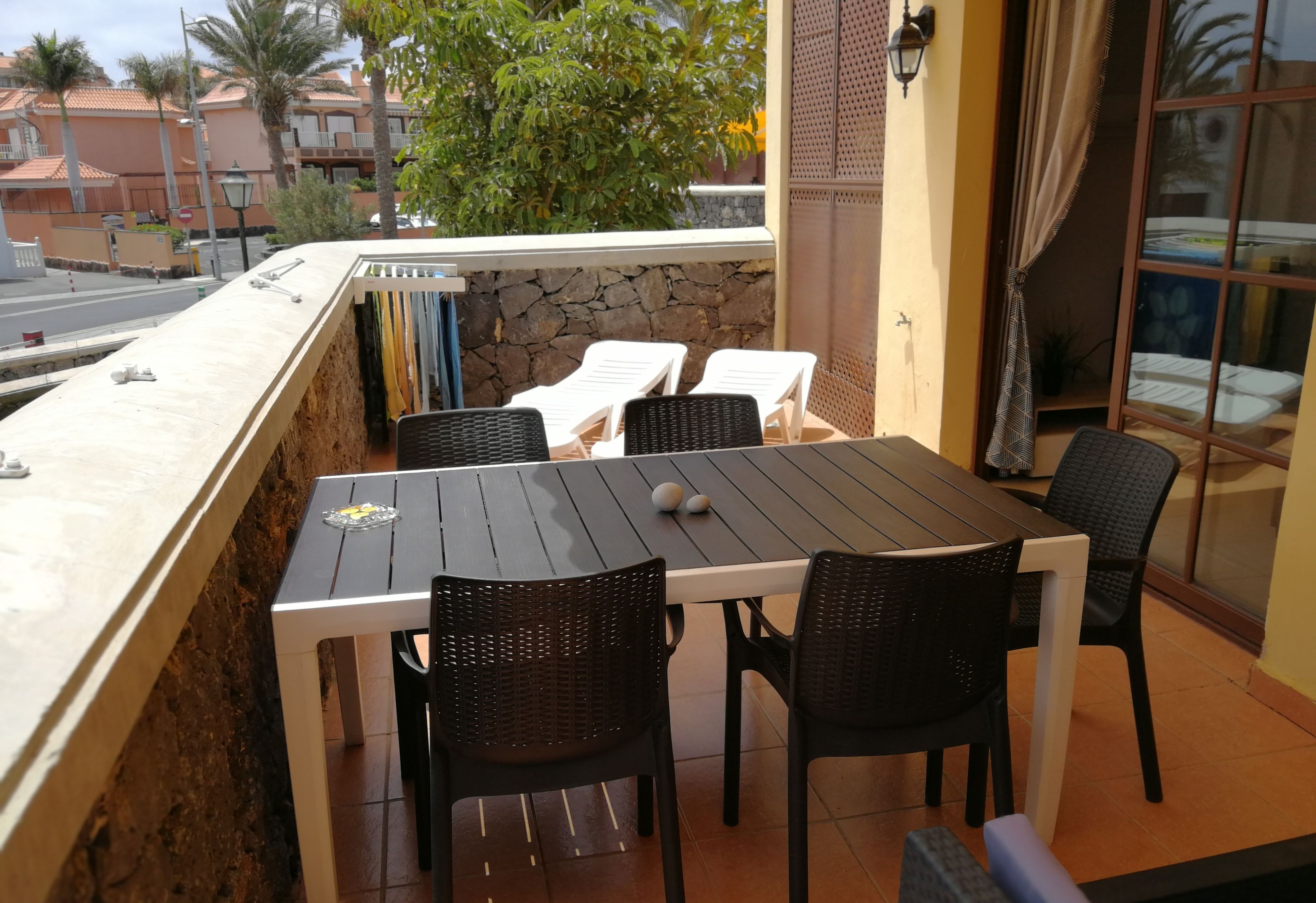 An outdoor patio with a stone wall, a table, and four chairs.