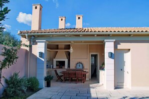 A patio with a brick fireplace, outdoor seating, and a door leading to the interior.