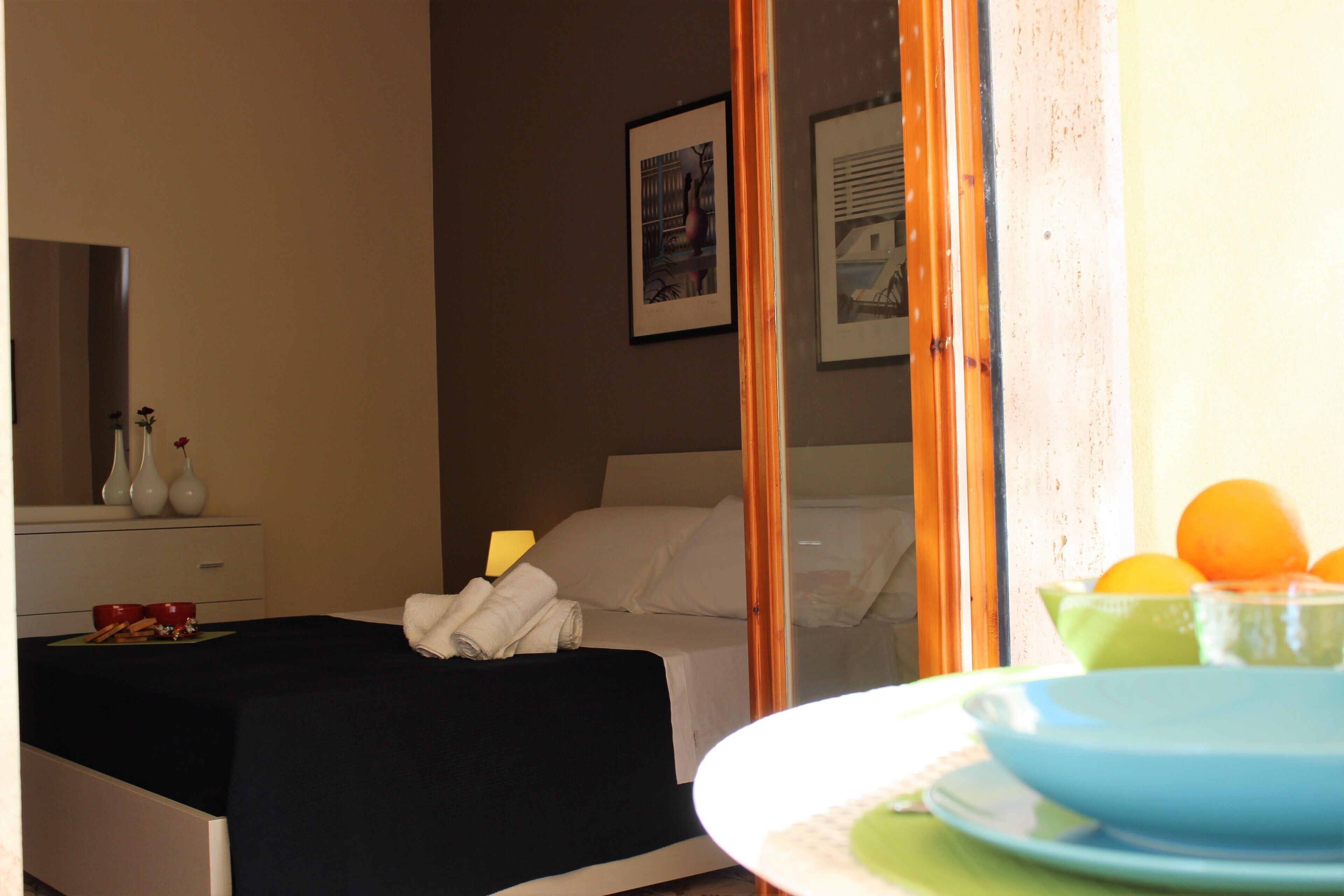 Ein Hotelzimmer mit Bett, Nachttisch mit Lampe, Spiegel und Fenster mit Ausblick.