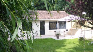 A white house with a tiled roof, a small patio with a table and chairs, and a grassy yard. - At the water wire Perigord (Lisle)