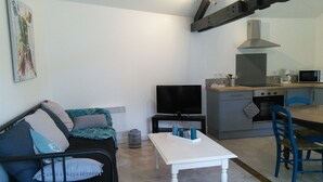 A compact living space with a sofa, a TV, a dining table, and a kitchen area. - At the water wire Perigord (Lisle)