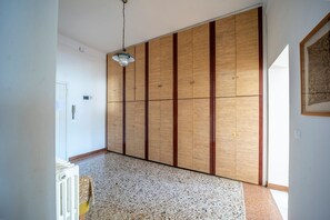 A hallway with a wooden wardrobe, a radiator, and a hanging light fixture.