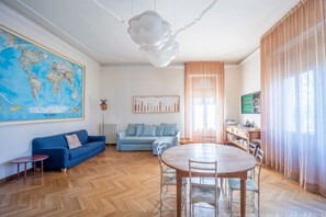 Un salon moderne avec une grande carte du monde, un canapé bleu, une table à manger en bois et un globe terrestre.
