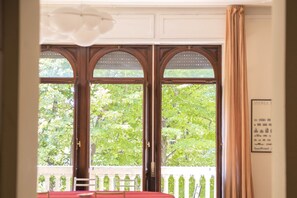 Una habitación con un ventanal grande, una mesa roja y una barandilla blanca.