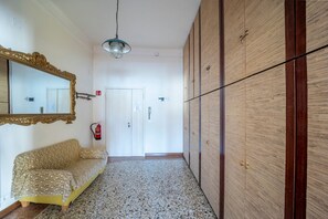 Un pasillo con un sofá estampado, un espejo grande, un armario de madera y un extintor.