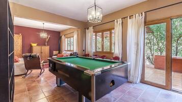 Enjoy a game of pool in this spacious room with a pool table, large windows, and comfortable seating.