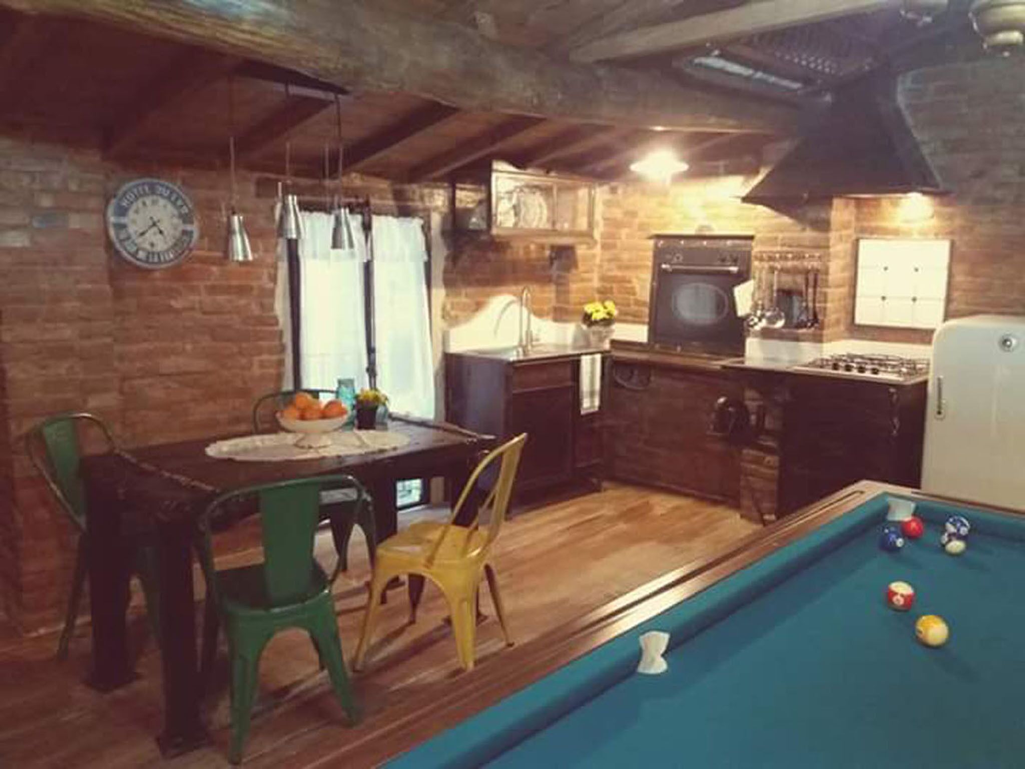 Une cuisine de taille réduite avec un coin repas, une table de billard et une horloge au mur.