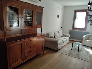 A living room with a wooden cabinet, a beige sofa, a glass coffee table, and a white armchair. - Wonderful Country House near Venice (Dolo)