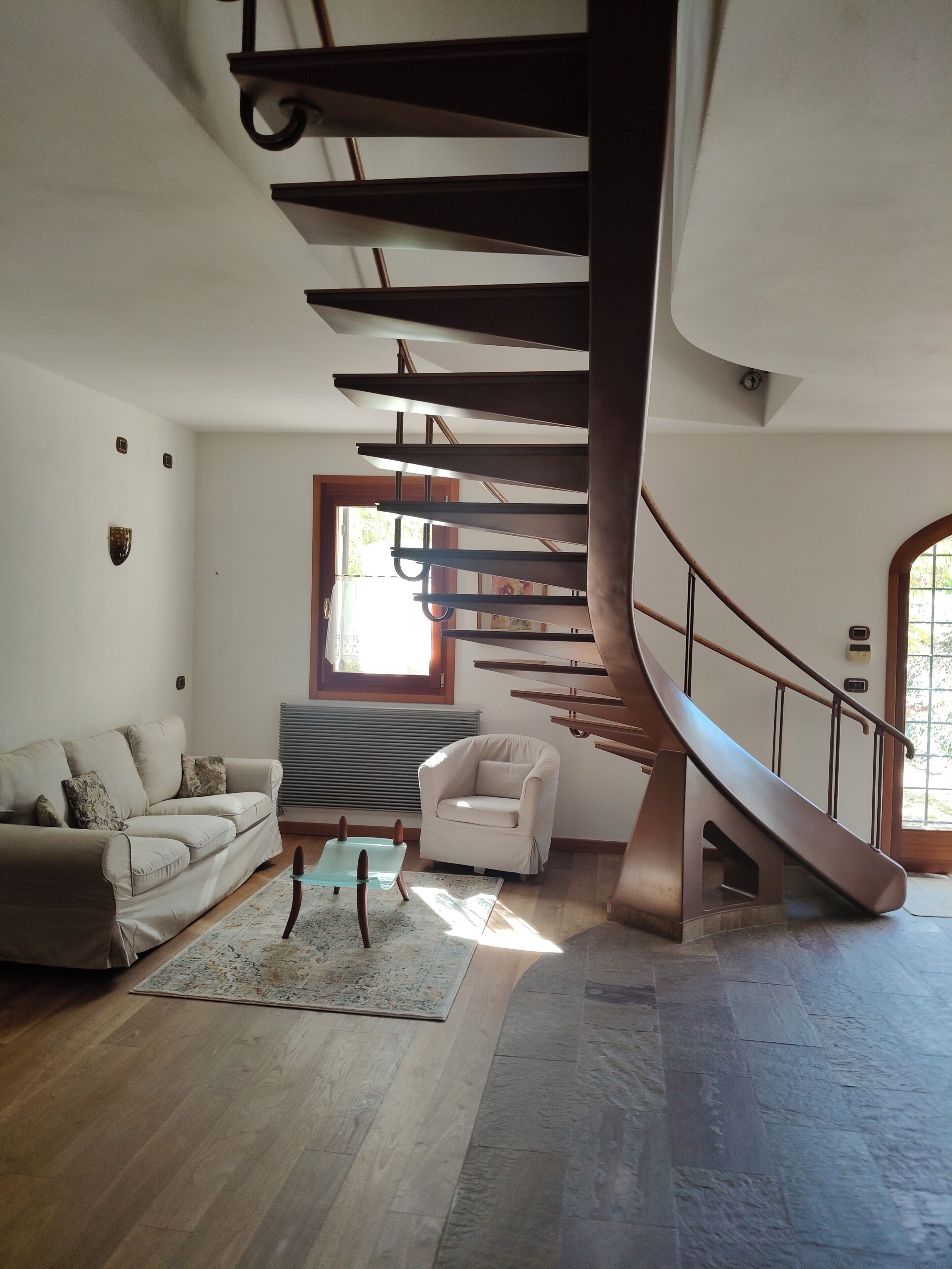 A modern interior with a spiral staircase, a sofa, a chair, and a small table.