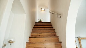 A wooden staircase with a handrail, a small potted plant at the top, and a light fixture above it. - Casa Resende - Resende House (Évora)