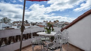 A balcony with a table and chairs, a potted plant, and a pink umbrella. - Casa Resende - Resende House (Évora)
