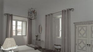 A bedroom with two beds, a bedside table with a lamp, a mirror, and a wardrobe. - Casa Resende - Resende House (Évora)