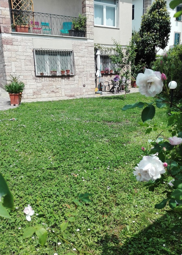 A residential area with a well-maintained lawn, potted plants, and a balcony with outdoor furniture.