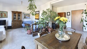 A dining area with a wooden table, chairs, and a vase with flowers. There are potted plants and a cabinet with glass doors. - HOW I WAS HOME: LARGE SPACES, WIFI, BIKE AND PRIVATE PARKING AND FLORENCE IS YOURS! (Firenze)