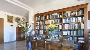 A library with a wooden bookshelf filled with books, a dining table with chairs, and a vase with flowers. - HOW I WAS HOME: LARGE SPACES, WIFI, BIKE AND PRIVATE PARKING AND FLORENCE IS YOURS! (Firenze)