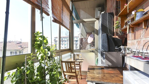 A small balcony with a wooden table and chairs, a potted plant, and a view of buildings in the background. - HOW I WAS HOME: LARGE SPACES, WIFI, BIKE AND PRIVATE PARKING AND FLORENCE IS YOURS! (Firenze)