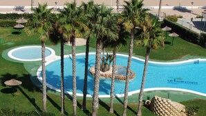 A swimming pool surrounded by palm trees and a well-maintained lawn. - ALICANTE, GREAT VIEWS, SUN FOUR SEASSON AND BEACH (3 BEDROOMS) WIFI (Urbanova)
