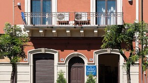 A two-story building with balconies, a flag, and a sign for 'Katane Holidays'. - Bellini Apartment with Balcony   (Catania)