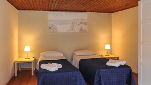 A room with two beds, each with a pillow and a folded towel. There are bedside tables with lamps. - Bellini Apartment with Balcony   (Catania)