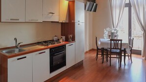 A modern kitchen with white cabinets, a stainless steel sink, and a wooden countertop. - Bellini Apartment with Balcony   (Catania)