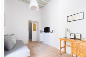 Een kamer met een bed, een bureau, een televisie en ingelijste foto's aan de muur.