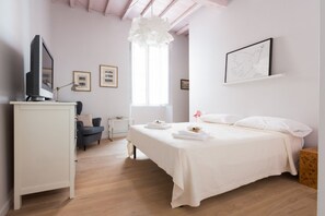 Une chambre à coucher avec un lit, un bureau, une chaise, un téléviseur et des tableaux encadrés au mur.