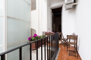 A balcony with a railing, potted plants, and a wooden chair. - Ideal Apartment Navona Square (Roma)