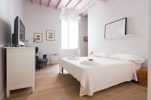 A bedroom with a bed, a desk, a chair, a TV, and framed pictures on the wall. - Ideal Apartment Navona Square (Roma)