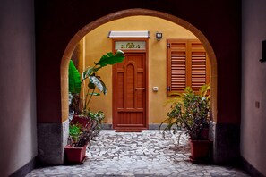 A courtyard with a tiled floor, a wooden door, and potted plants.