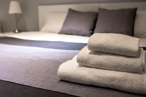 A neatly made bed with a grey bedspread and two pillows.