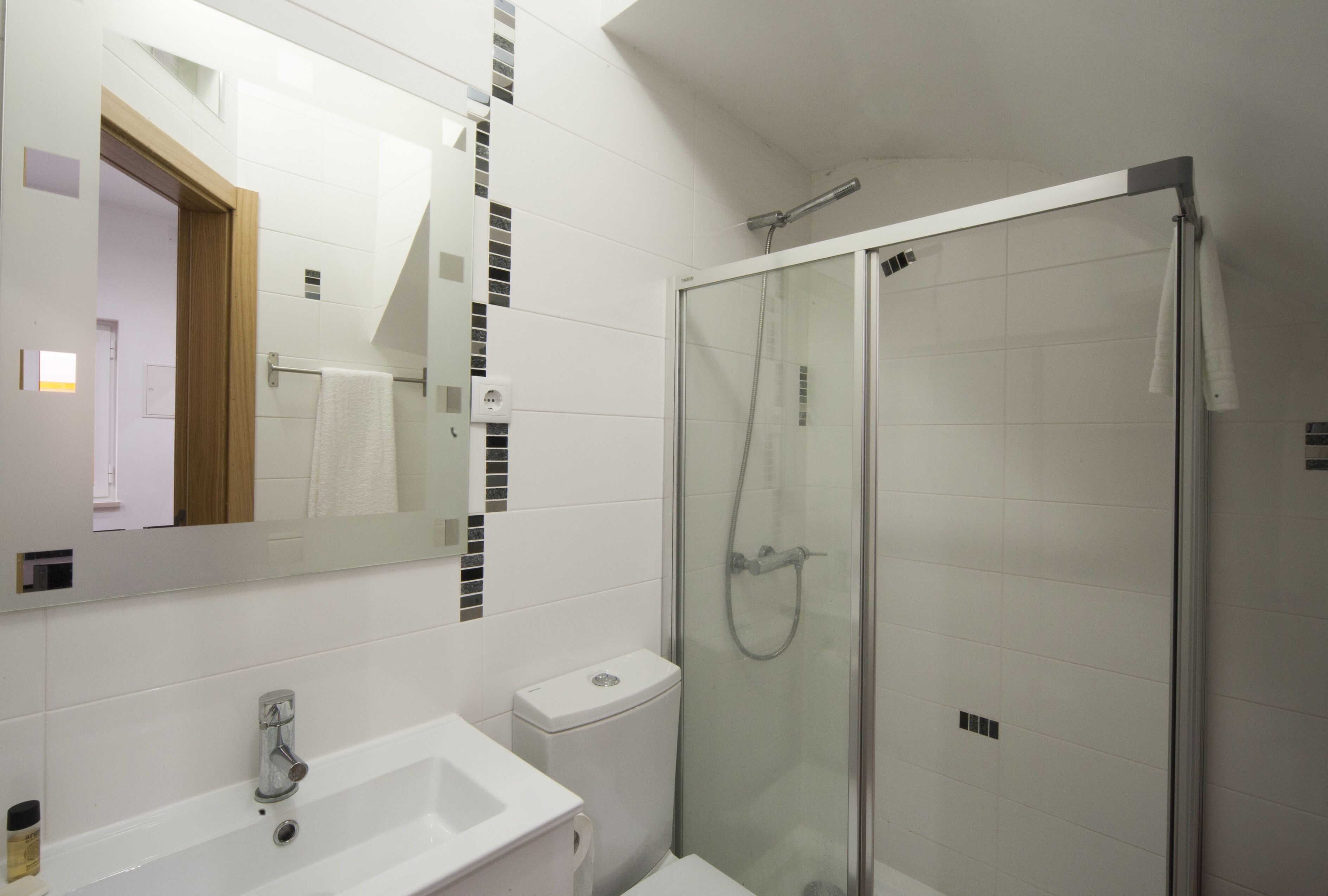 A modern bathroom with a glass-enclosed shower, a white sink, and a large mirror.
