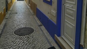 A narrow cobblestone street with a blue and white building. There is a door with a number '5' above it. - Fertile Dreams-Freedom 10 meters from the beach (Nazaré)