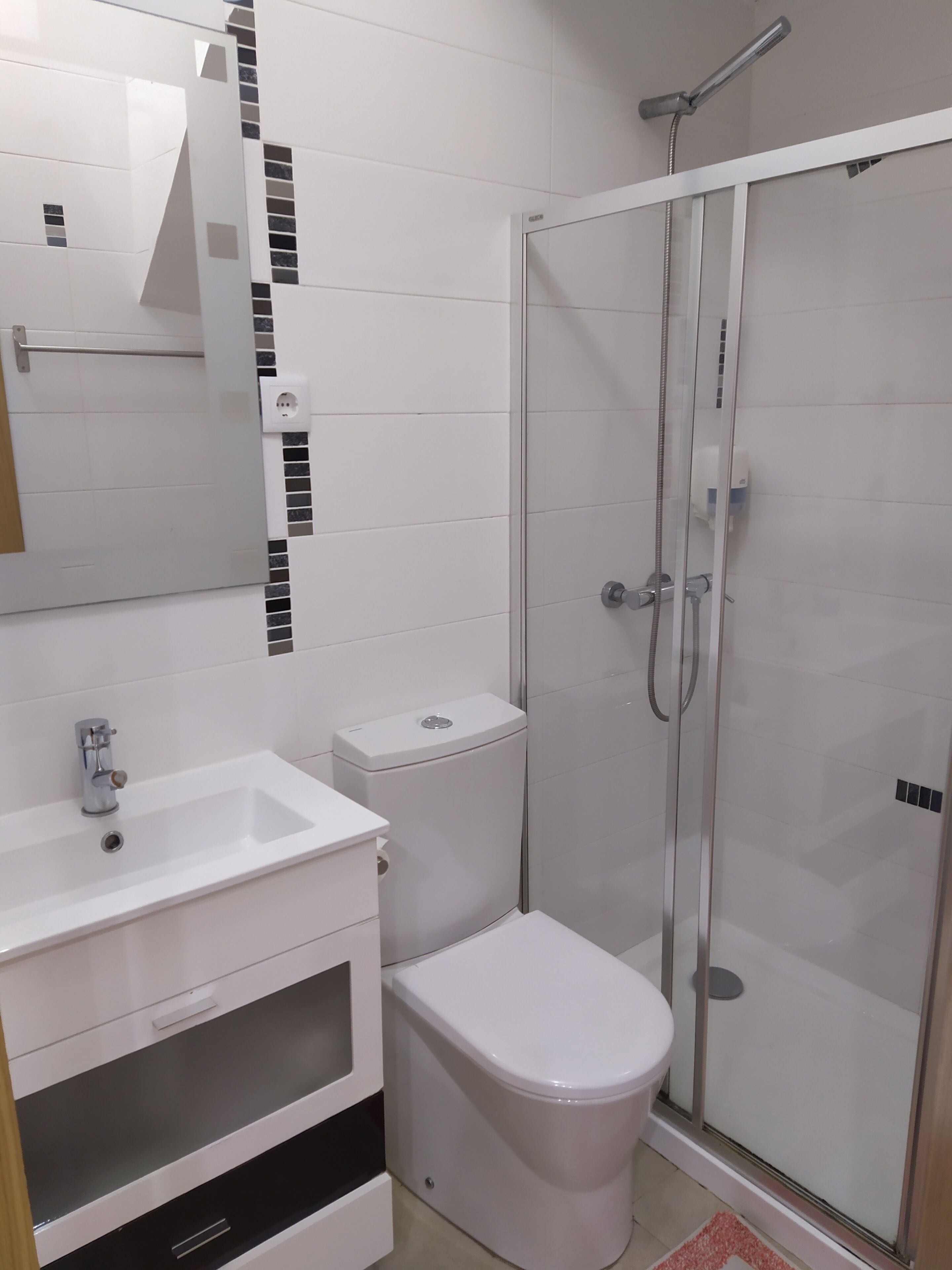 Une salle de bain moderne avec une douche à parois de verre, un lavabo blanc et des toilettes.