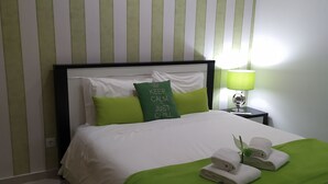 A neatly made bed with green bedding, a pillow with 'KEEP CALM JUST CHILL' text, and a green rug. - Fertile Dreams-Freedom 10 meters from the beach (Nazaré)