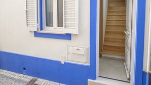 A building with a blue and white facade, a wooden staircase leading to an interior, and a window with white shutters. - Fertile Dreams-Freedom 10 meters from the beach (Nazaré)