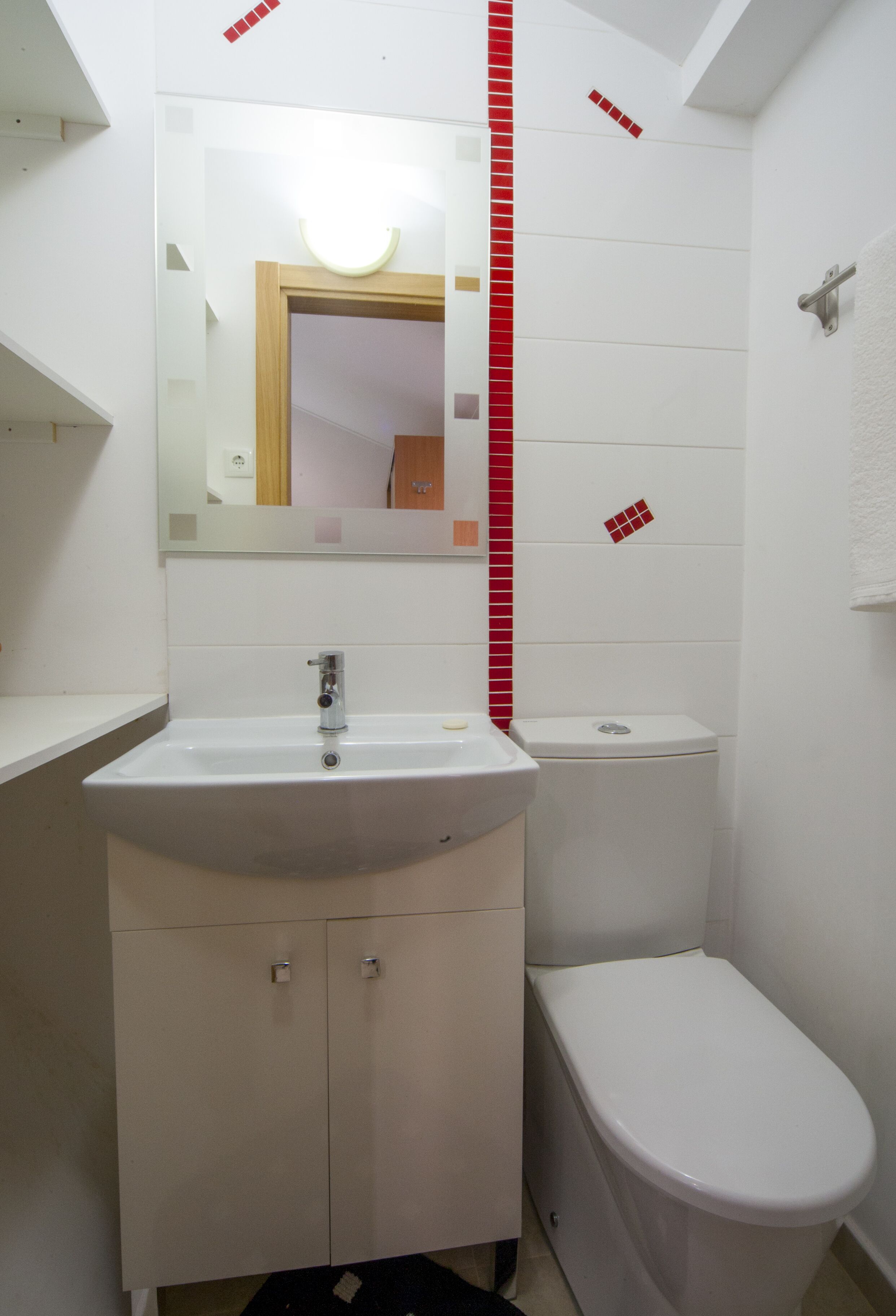 A small, compact bathroom with a white sink, mirror, and toilet.