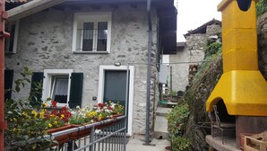 Un bâtiment en pierre doté d’un balcon, d’une porte et d’une fenêtre avec des volets.