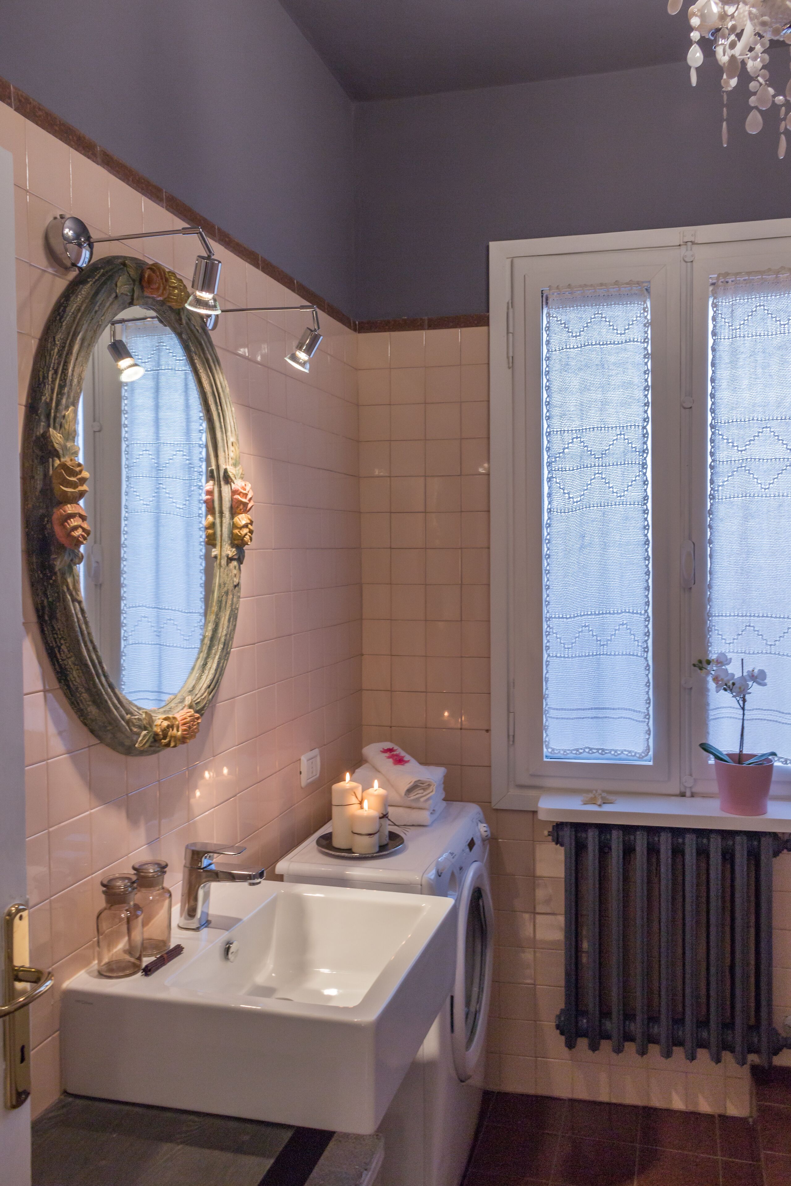 A bathroom with a large mirror, a sink, a washing machine, and a radiator.