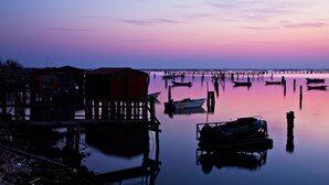Una tranquilla zona sul lungomare con barche ormeggiate e un molo che si protende nell'acqua.