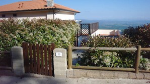 A building with a tiled roof, a wooden gate, and a view of the landscape. - Watching The Horizon in residence with swimming pool for a fee (Monteverdi Marittimo)