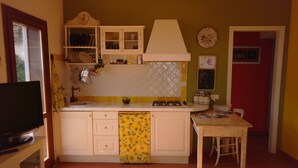 A compact kitchen with white cabinets, a yellow backsplash, and a dining area with a wooden table and chairs. - Watching The Horizon in residence with swimming pool for a fee (Monteverdi Marittimo)