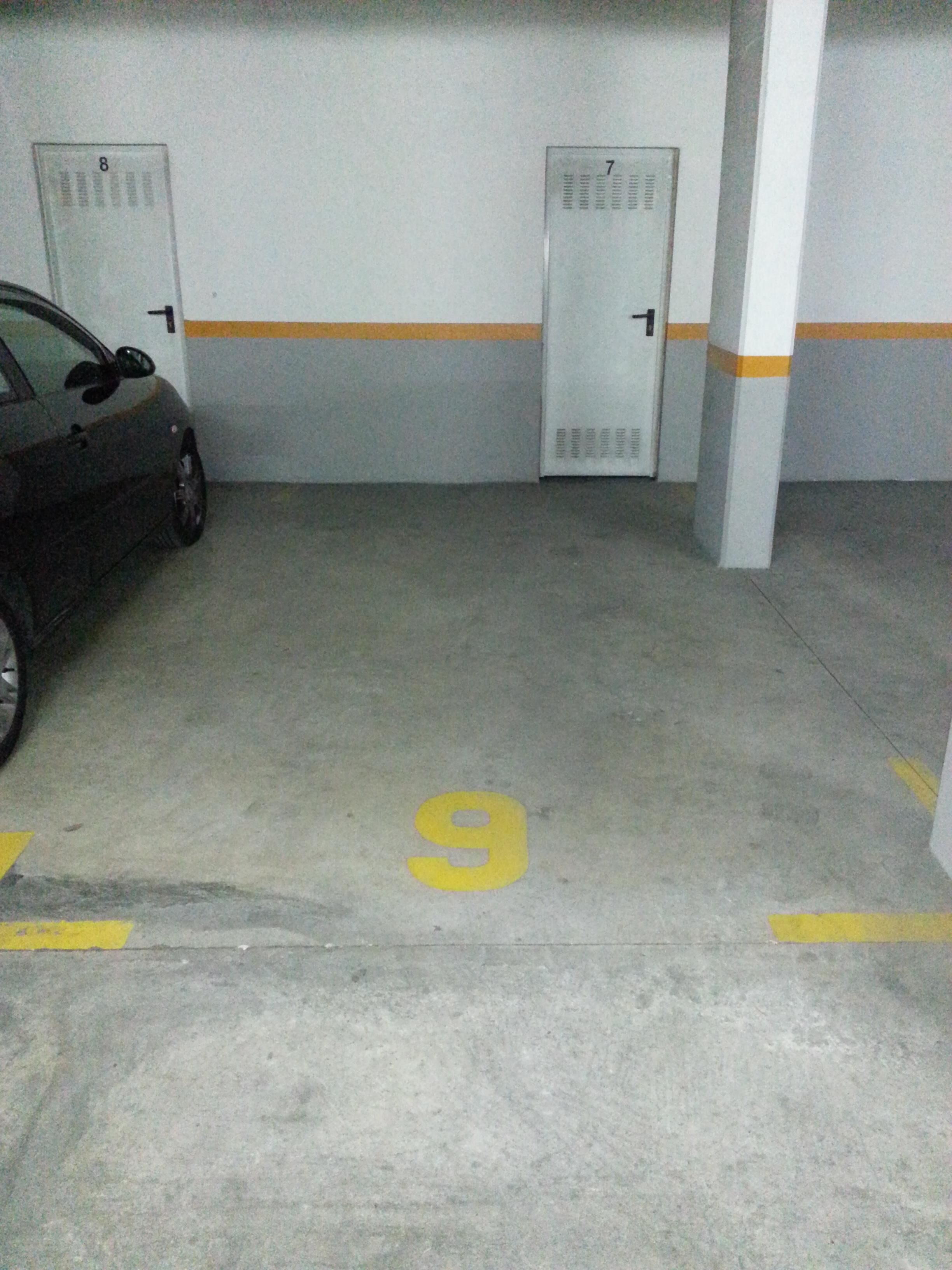 Eine Parkgarage mit nummerierten Stellplätzen, ein Auto auf Platz Nummer 9 und Türen mit den Nummern 7 und 8.