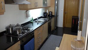 Una cocina con gabinetes de madera, estufa de acero inoxidable, un fregadero y un refrigerador.