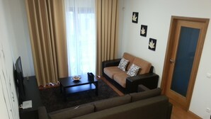 Una sala de estar con un sofá, una mesa de centro, un televisor y una puerta.