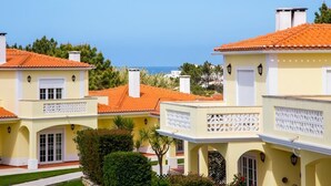 A row of yellow buildings with orange tiled roofs and white balconies, overlooking a clear blue sky. - Apartment in Praia D'El Rey Golf & Beach Resort (Amoreira)