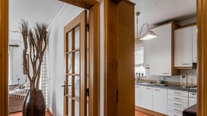 A kitchen with white cabinets, a tiled backsplash, and a hanging pendant light. - Apartment in Praia D'El Rey Golf & Beach Resort (Amoreira)