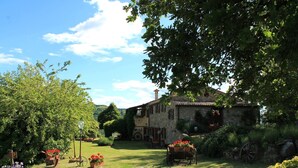 A rustic stone house with a garden, a wheelbarrow, and a sign with a letter 'P'.